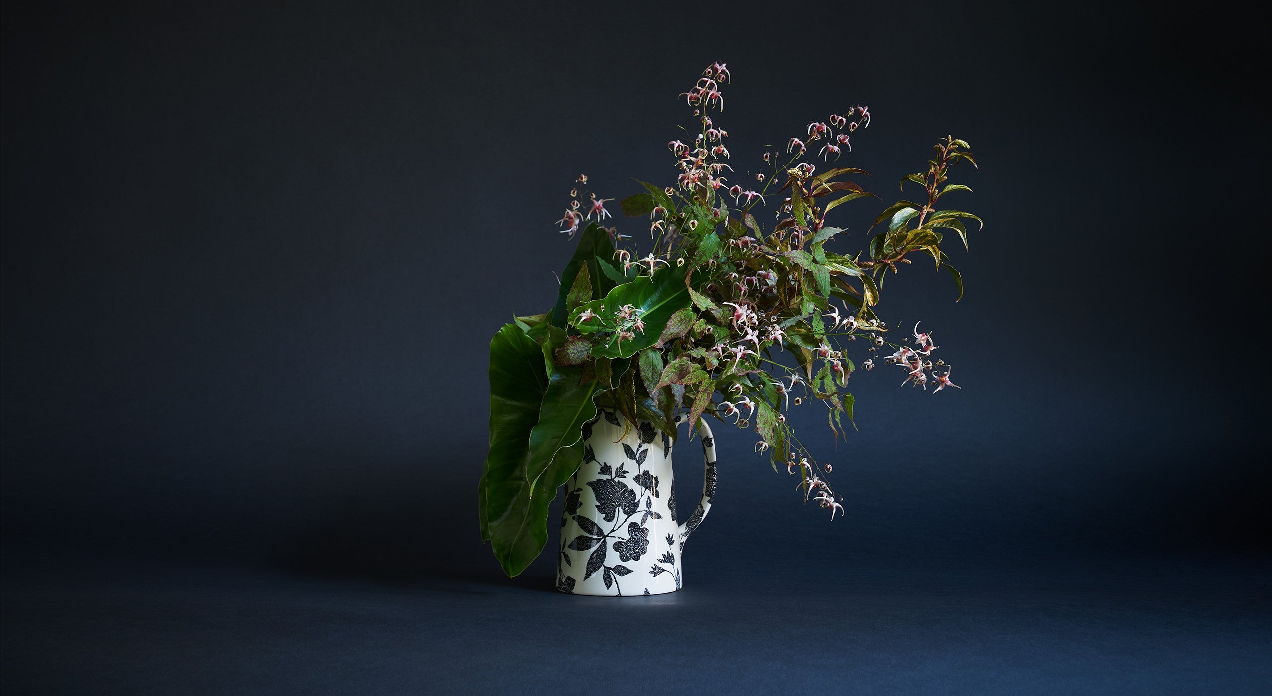 &ldquo;Questa &egrave; una scelta perfetta se si desidera creare una composizione dal sapore boschivo. Al centro di questa creazione c&rsquo;&egrave; l&rsquo;epimedium, un fiore da giardino davvero molto comune caratterizzato da un bellissimo fogliame e da una breve fioritura in primavera. &Egrave; tutta questione di texture e screziature, qualcosa su cui amo ritornare continuamente. Quando creo una composizione, voglio che le persone provino a osservarla un po&rsquo; pi&ugrave; attentamente di quanto non farebbero normalmente. Qui &egrave; presente anche il leucothoe &ndash; un comune arbusto molto resistente e spesso ingiustamente snobbato &ndash; e il filodendro, una pianta d&rsquo;appartamento che in vaso ha una vita lunghissima. Ho provato a trasformare il loro aspetto ceroso e tropicale, facendoli assomigliare a qualcosa che potrebbe trovarsi in una zona umida e acquitrinosa&rdquo;.