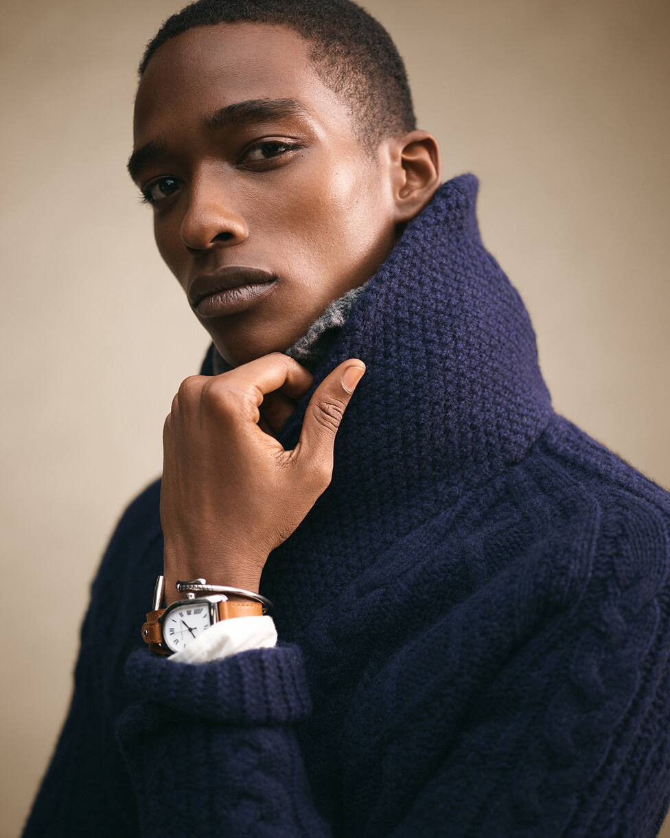 Primo piano di un uomo che indossa una maglia a trecce blu navy scuro con collo alto.